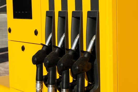 A bright yellow gas station displays four fuel dispenser nozzles ready for use photo