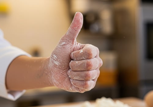 A chef giving a thumbs up while holding a dough ball photo