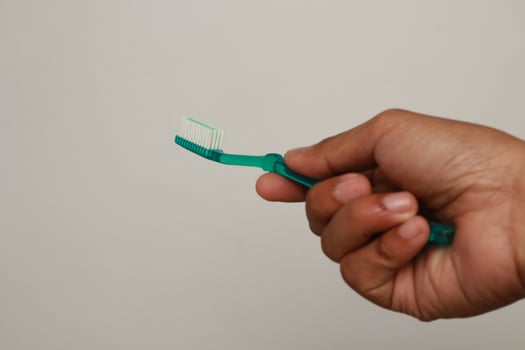 Close-up of a hand holding a green toothbrush for oral hygiene maintenance photo