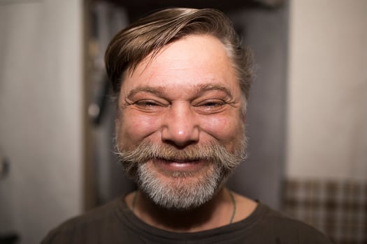 A man with a beard and mustache is smiling happily for the camera photo