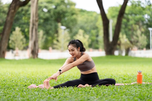 Outdoor yoga practice. Young woman stretching her legs on a yoga mat in a park. photo