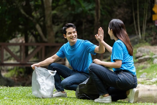 Volunteer teamwork. Two individuals high-fiving after cleanup effort. photo