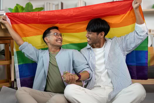 Happy gay couple celebrating love with pride flag in their new home photo