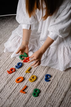 young woman holding multi-colored wooden numbers in her hand photo