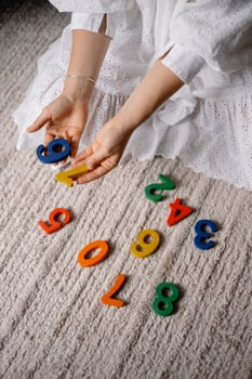 young woman holding multi-colored wooden number in her hands photo