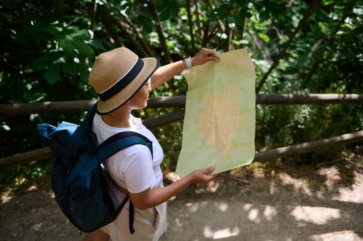 Woman Explorer Holding Map in Forested Pathway During Daytime Journey photo