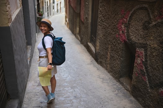 Young Woman Tourist Exploring a Historic European Alleyway with a Map and Backpack photo