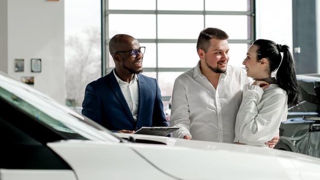 A black dealer advises a couple on buying and test driving a new car in a modern car dealership. The concept of buying, renting and successful family life photo