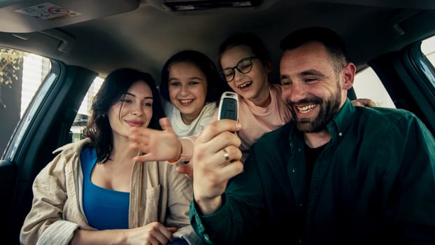 A happy young family gets the keys to their new car at a modern car dealership. The end of a test drive or purchase of a new car photo