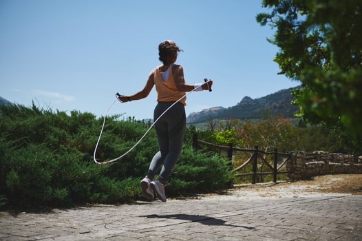 Woman Exercising Outdoors with a Jump Rope in a Scenic Mountain Setting photo