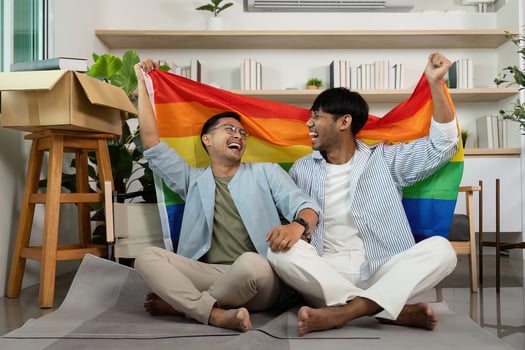 Gay couple celebrating love with rainbow flag indoors photo