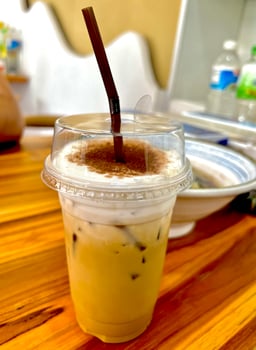 A cup of iced coffee with a straw on top of a wooden table photo