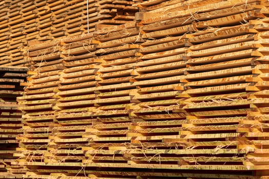 Wooden boards are stacked in a sawmill. Timber processing at the sawmill. Woodworking industry photo