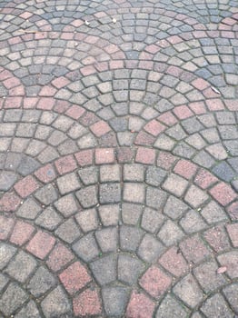 The image displays a surface paved with cobblestones, arranged in a decorative, fan-like pattern photo