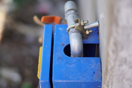 A small pipe leading into a water flow control box in a building. photo