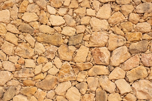 Natural stone wall texture in Spain with warm tones and varied shapes enhances the rustic charm of the landscape photo