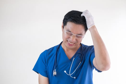 An Asian male nurse or doctor in blue scrubs and gloves showing signs of frustration and stress photo