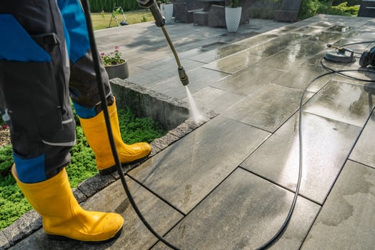 Professional Cleaning of Outdoor Stone Patio Using Pressure Washer and Protective Gear photo