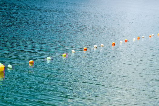 Bright buoy markers floating along a tranquil lake during a sunny day photo