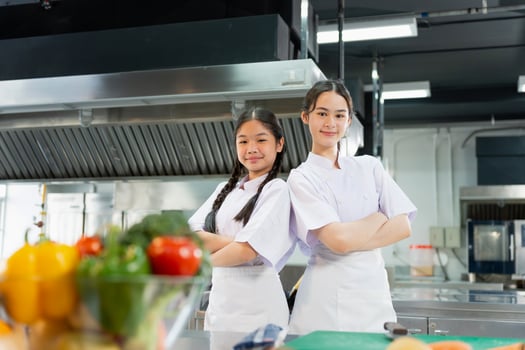 Two Confident Culinary Students in Professional Kitchen, Young Asian Female Chefs Posing in a Modern Kitchen photo