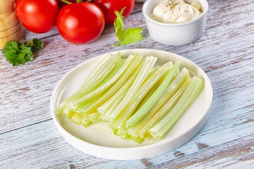 Celery sticks on a plate with a bowl of sour cream photo