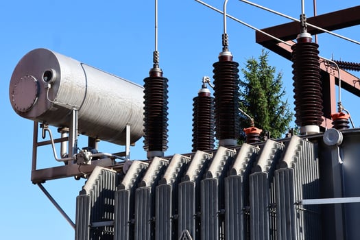 High-voltage insulators and electrical components of a power substation outdoors, surrounded by trees. Industrial electricity distribution infrastructure. photo