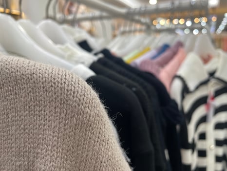 Close-Up of Knitted Fabric Texture with Elegant Clothes on Hangers in Fashion Boutique photo