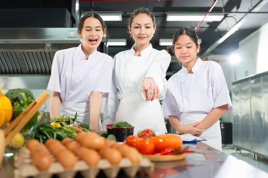 Professional Chef Mentoring Young Cooks in a Bright Kitchen, Chef and Students Learning Culinary Skills in Kitchen, Women Preparing Fresh Ingredients for Cooking Class photo