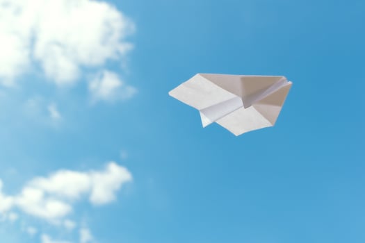 Paper plane flying against blue sky photo