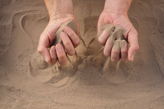 Sand of time. Close-up of sand falling from man's hand. photo