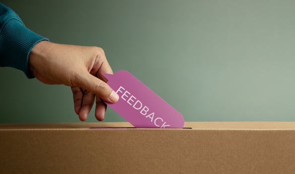 Hand putting feedback card in box symbolizing customer review, survey response, and constructive evaluation photo