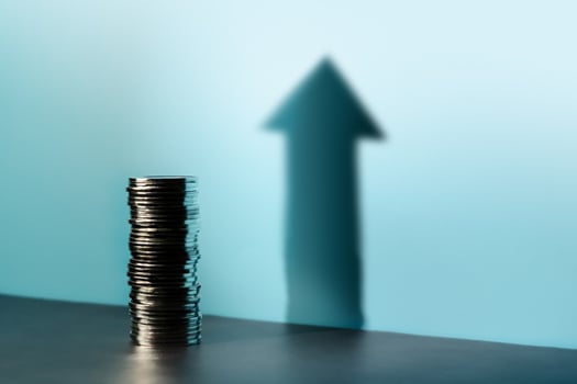 Coins stacked cast a tall upward arrow shadow, reflecting financial growth, investment optimism, and a hopeful economic outlook photo