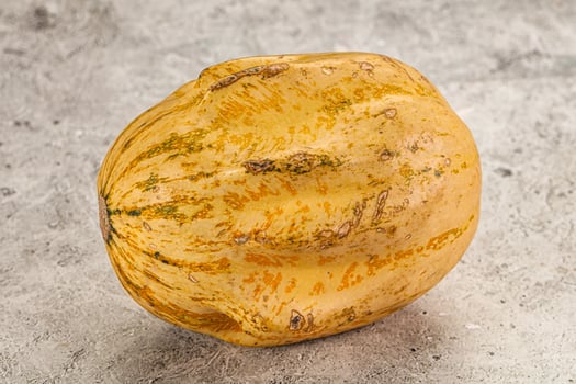 A yellow squash on a gray surface photo