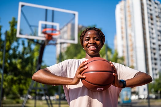 Young black female practicing basketball on a city court, showcasing her active lifestyle and passion for the sport. photo