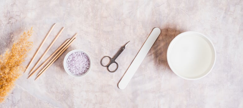Manicure scissors, nail file, water, salt and nail sticks top view web banner photo