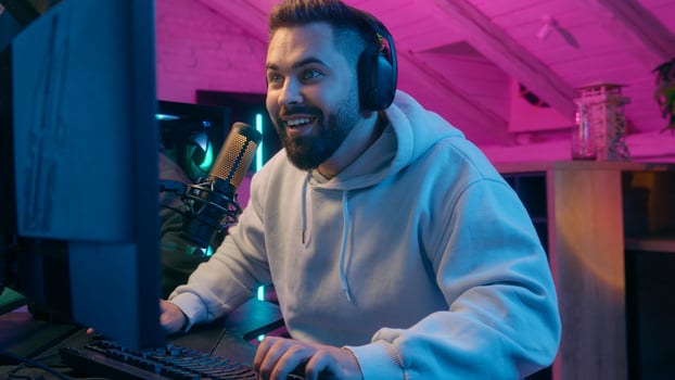 Excited winner champion Caucasian guy male gamer streamer man winning luck achievement victory internet win talking microphone play online game addict in headphones gaming streaming in neon dark room photo