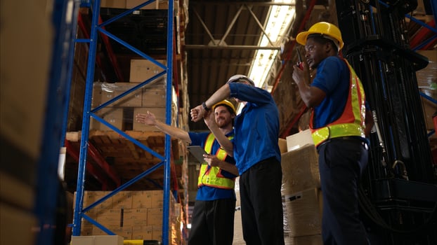 A bunch of warehouse workers are reviewing the list of items based on the documentation,76 photo