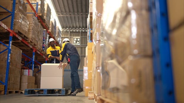 Two warehouse workers are lifting boxes of merchandise on a pallet jack to store on a shelf in a warehouse,66 photo