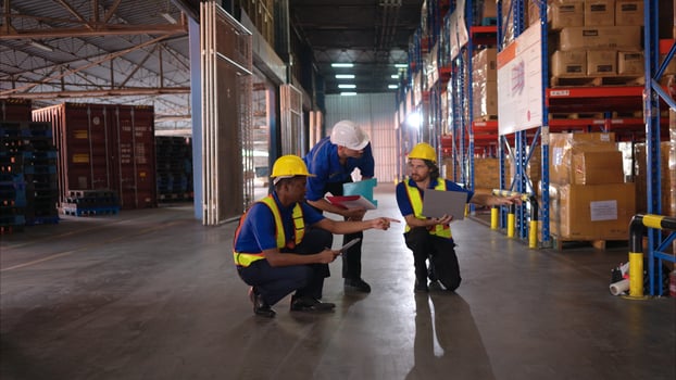 A bunch of warehouse workers are reviewing the list of items based on the documentation,9 photo