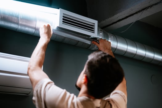 Technician repairing air duct system in modern interior during daytime photo