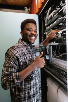 Technician organizes network equipment while smiling in data center during afternoon hours photo
