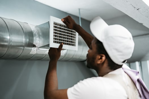 Worker installing air duct vent in a residential basement during the day photo