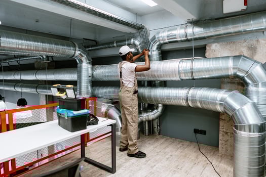 Skilled worker installing ventilation system in modern commercial building during daytime photo