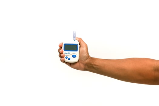 Hand holding a glucometer for blood glucose monitoring on white background photo
