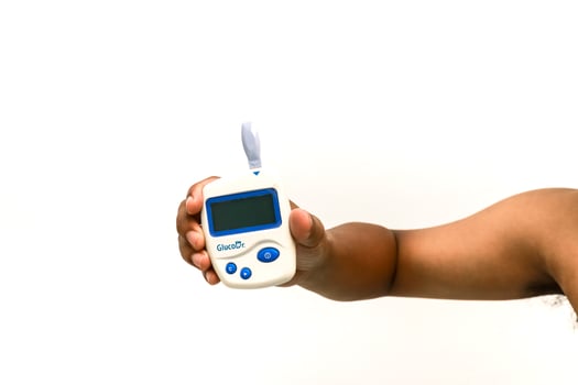 Hand holding glucometer for monitoring blood sugar levels with diabetes isolated photo