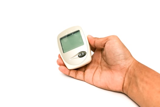 Hand Holding a Glucose Meter for Diabetes Monitoring on a White Background photo