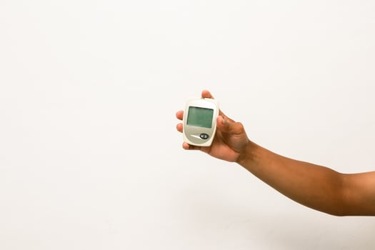 Hand holding glucose meter for checking blood sugar levels, diabetes control and monitoring concept, white background photo