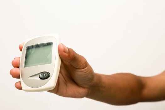 Close-up of hand holding glucose meter for blood sugar level measurement photo