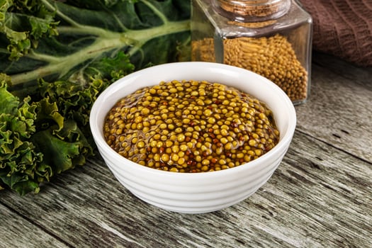 A bowl of mustard and a bottle of mustard on a table photo