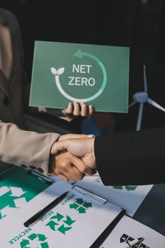 Two people shaking hands over a net zero sign photo